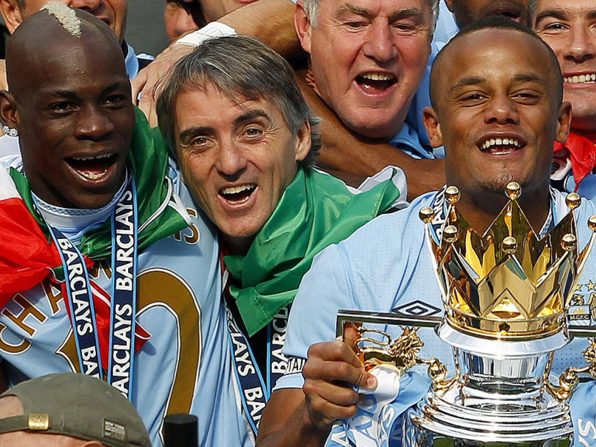 Manchester City kapten, Vincent Kompany, håller hårt i segertrofén med managern Roberto Mancini och Mario Balotelli vid sin sida efter 3-2-segern mot Queens Park Rangers, en vinst som säkrade ligasegern i Premier League. Foto: Dave Thompson, AP Photo/PA/Scanpix